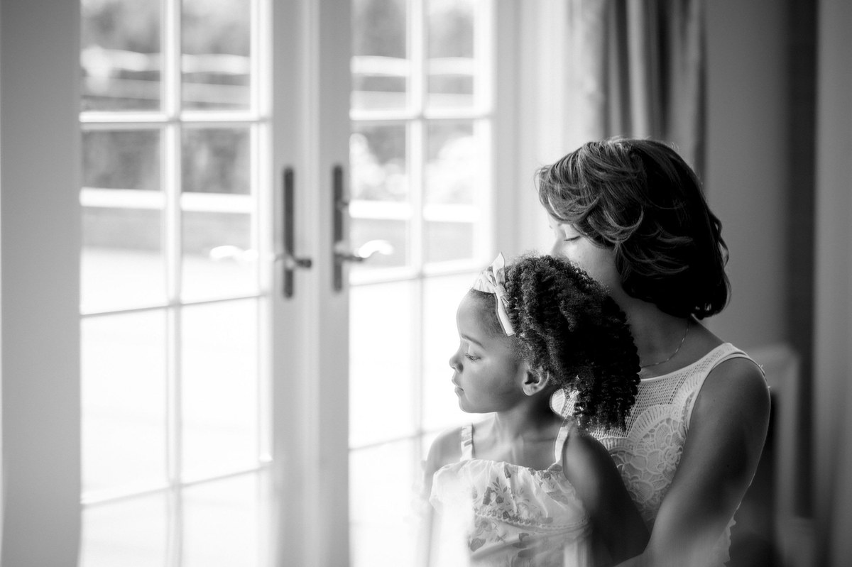 Black and white photo of a woman and young girl looking out a window together