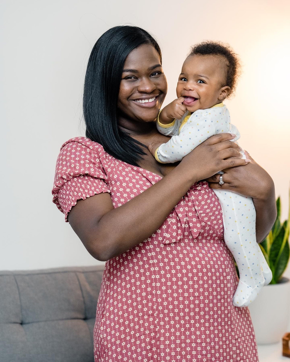 Woman in a pink polka-dot dress holding a smiling baby