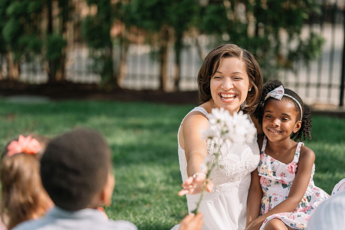 Woman and young girl smiling on a lawn while a boy looks on