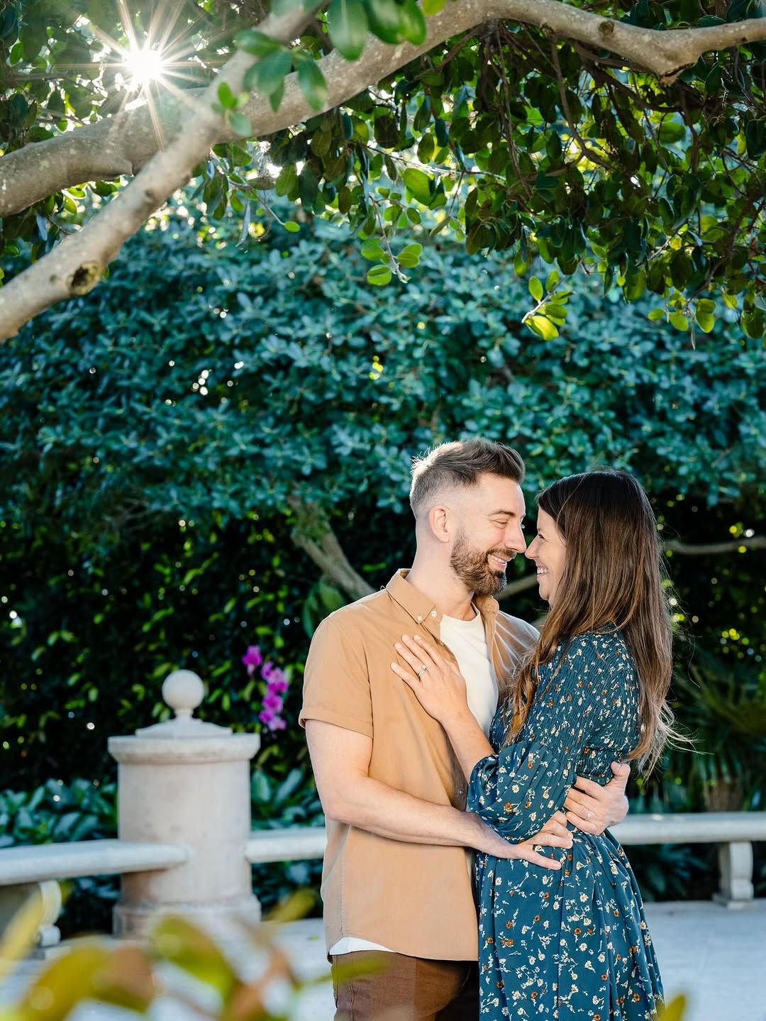 Couple embracing beneath tree branches in a garden
