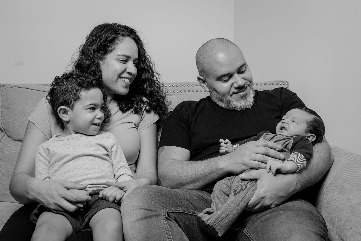 Black and white photo of a family on a couch, the father holding a newborn