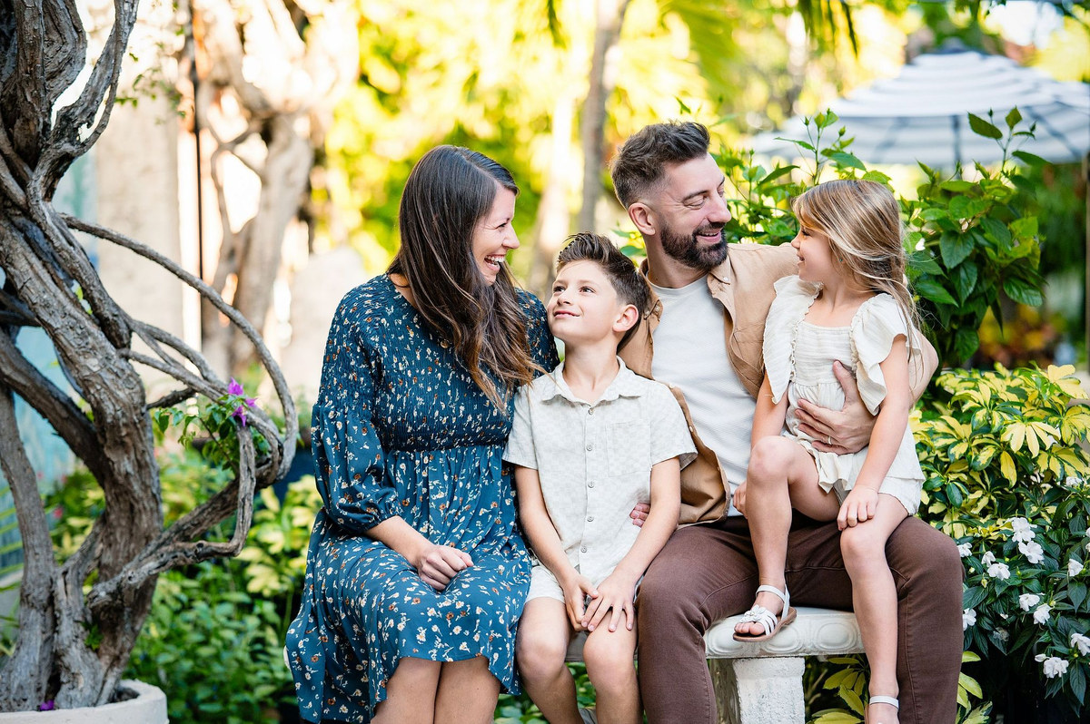Family of four sitting together on a garden bench