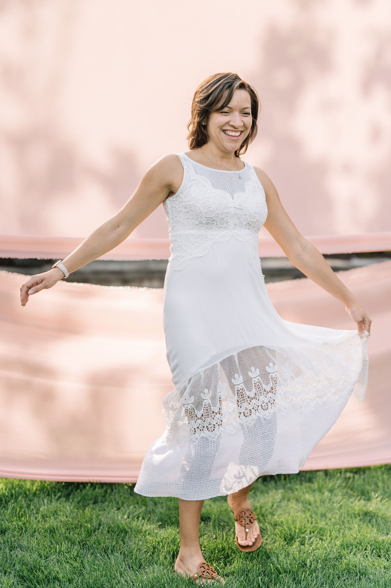 Woman in a white lace dress twirling her skirt on a lawn