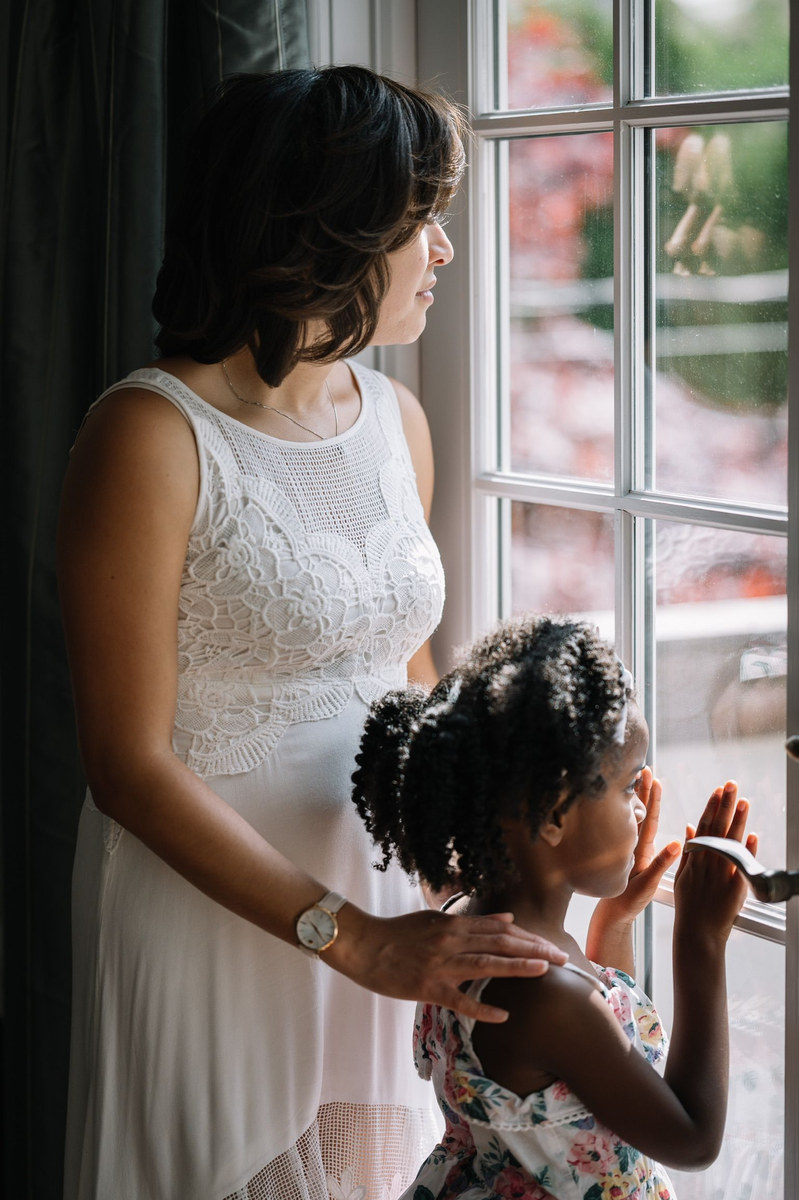 Woman and young girl looking out a window together
